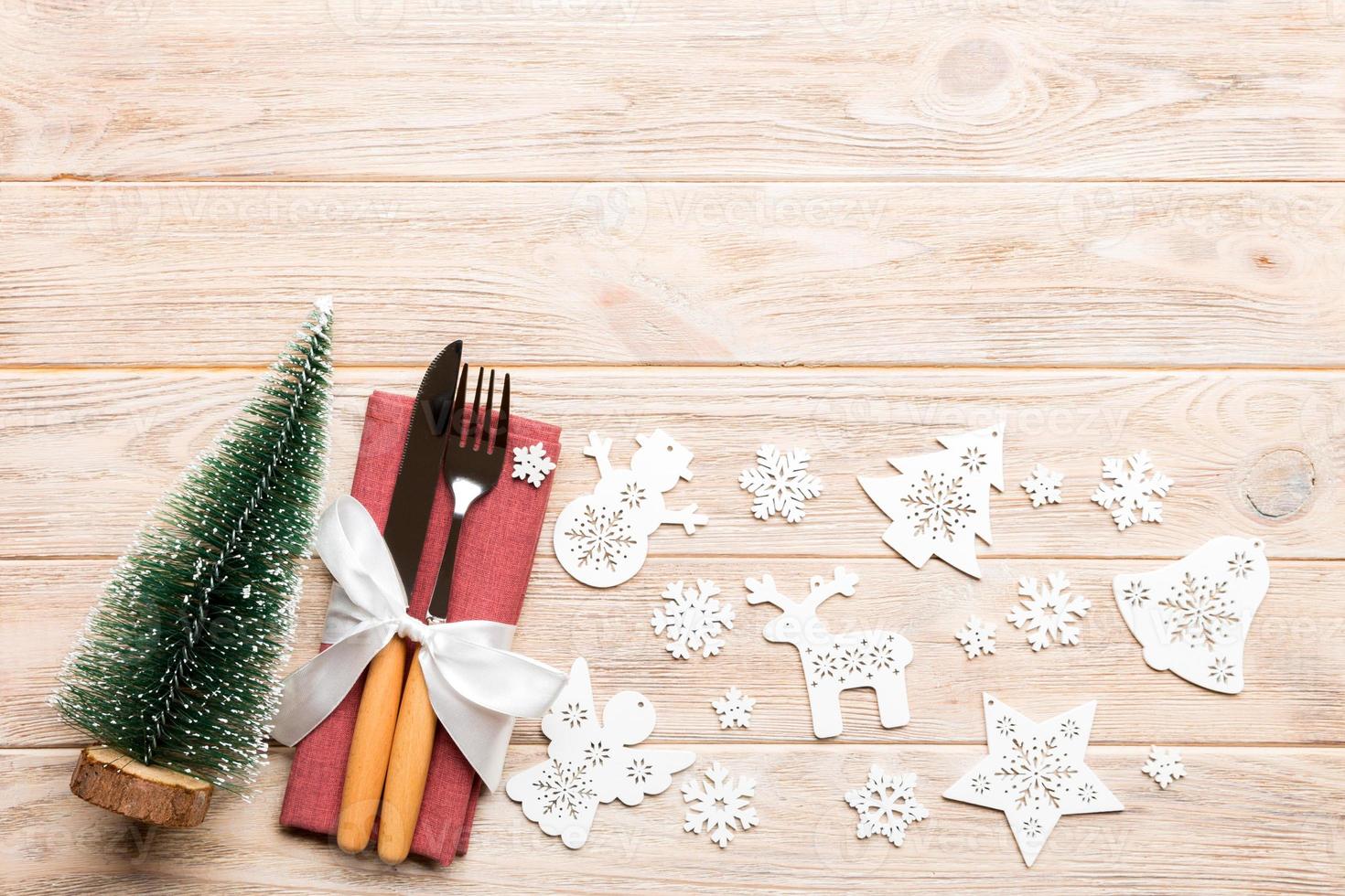 vue de dessus de la fourchette et du couteau attachés avec du ruban sur une serviette sur fond en bois. décorations de noël et arbre du nouvel an. concept de joyeuses fêtes avec un espace vide pour votre conception photo