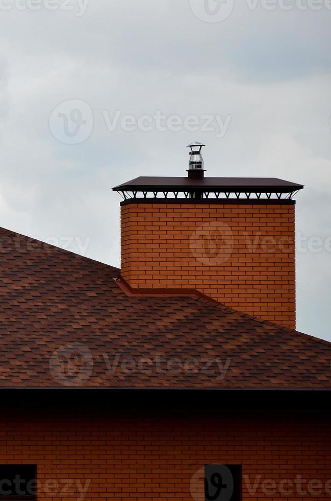 la maison est équipée d'une toiture de haute qualité en tuiles bitumineuses en bardeaux. un bon exemple de toiture parfaite. le toit est protégé de manière fiable contre les intempéries photo