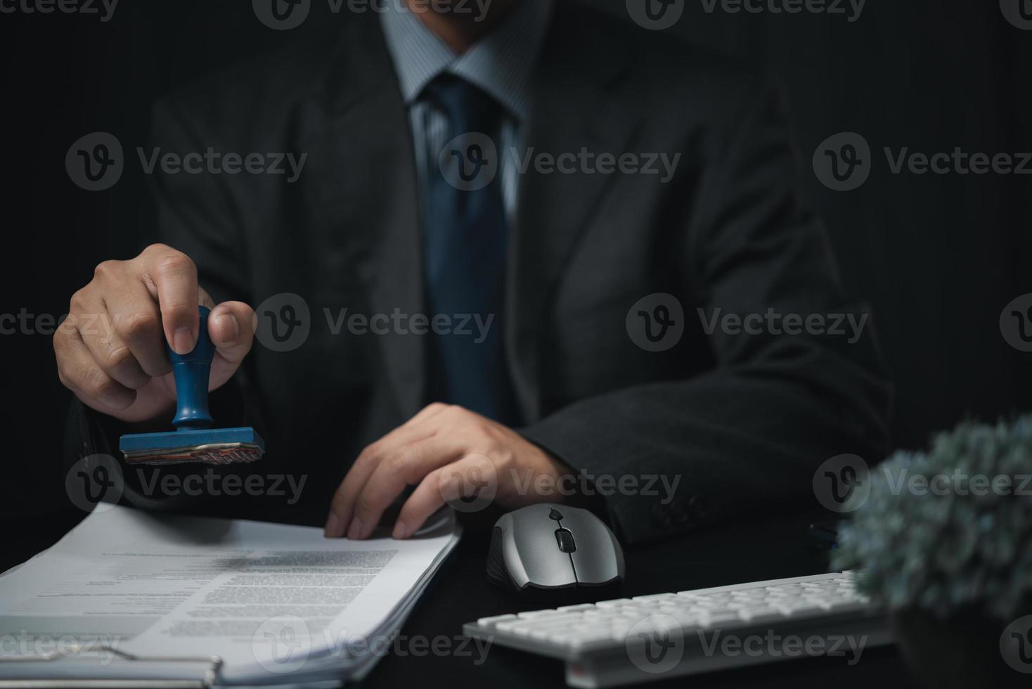 homme tamponnant l'approbation des documents bancaires de financement du travail ou de marketing d'investissement sur le bureau. photo