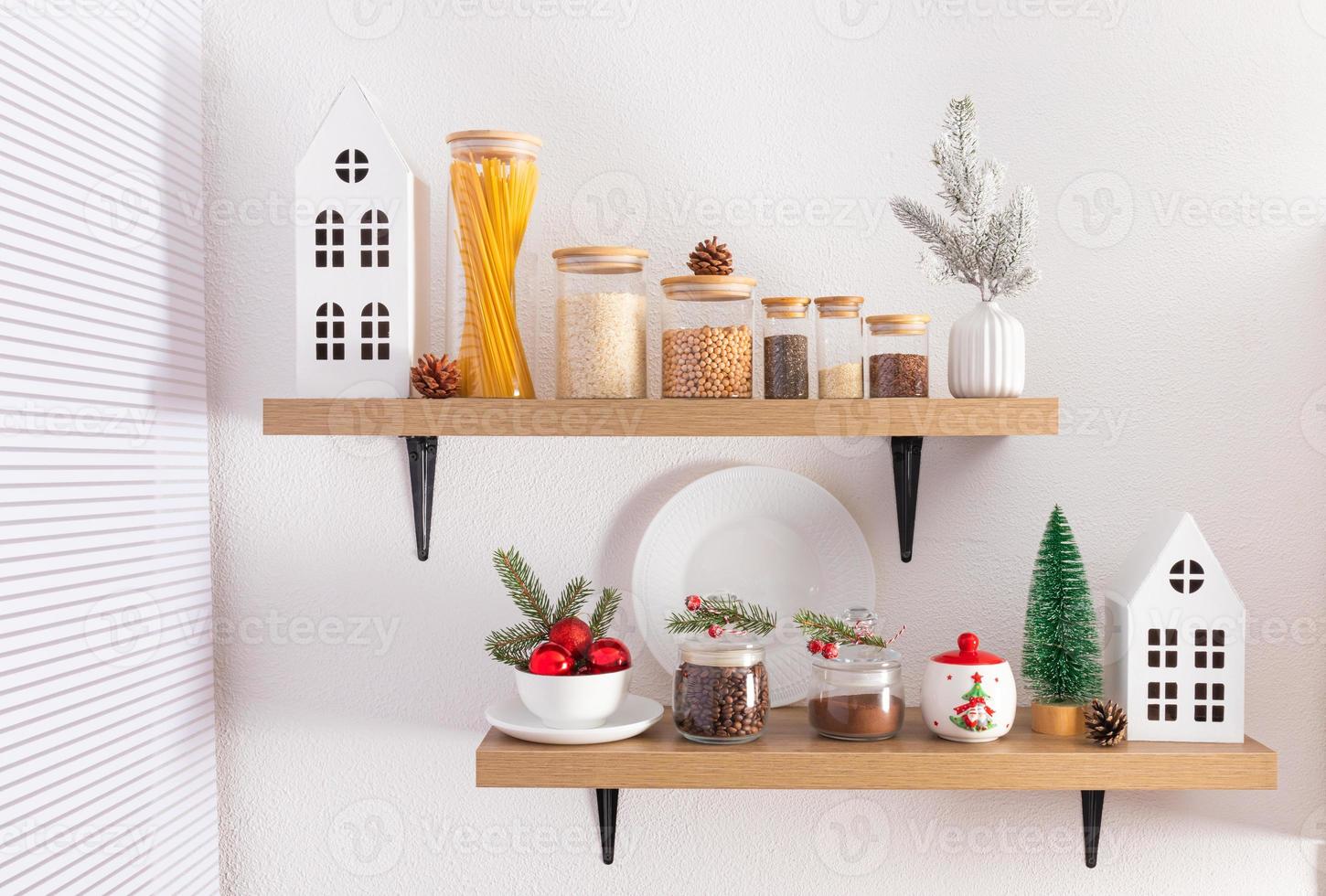étagères de cuisine ouvertes sur un mur texturé blanc avec divers pots de produits en vrac, café et décorations de noël. le concept d'un intérieur festif. photo