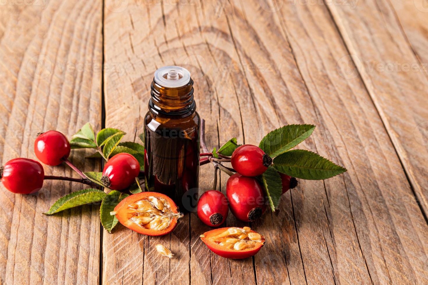 bouteille médicale en verre avec un compte-gouttes d'essence essentielle de masoa ou de graines de rose musquée avec des fruits frais sur un fond en bois. spa. aromathérapie. photo