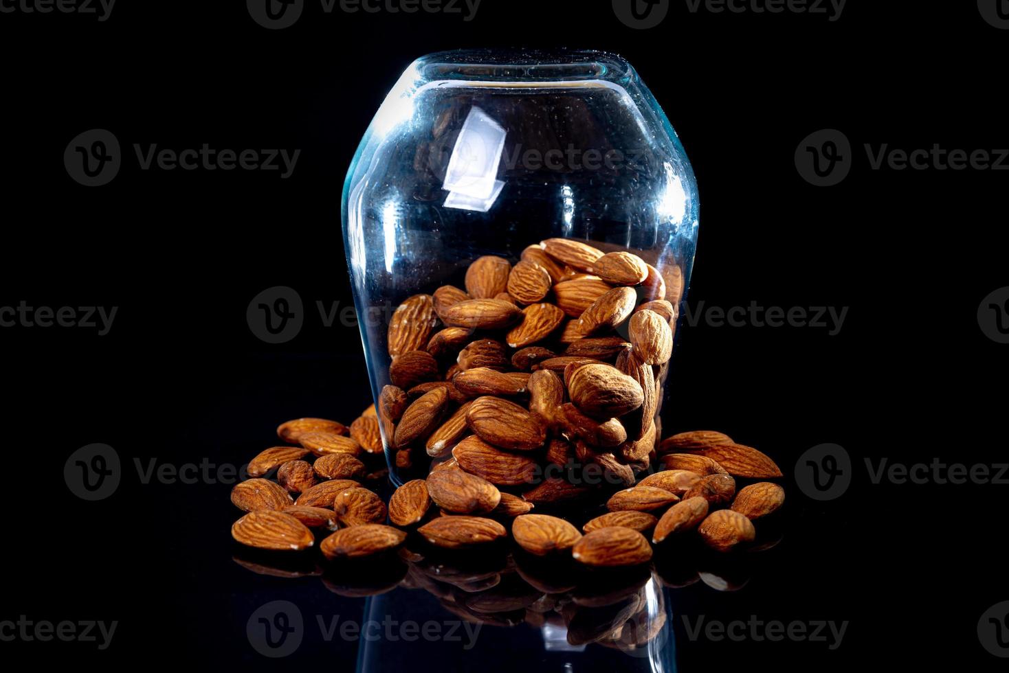 amandes pelées dans un seau de verre à vin en pot sur fond noir isolé. rangée de bols aux amandes, vue de face. photo