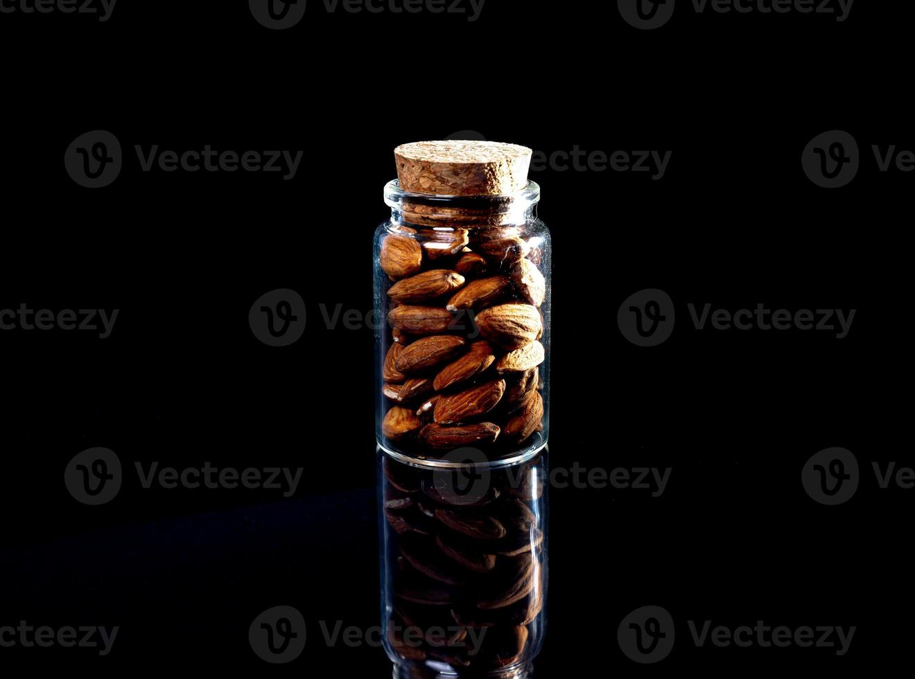 amandes pelées dans un seau de verre à vin en pot sur fond noir isolé. rangée de bols aux amandes, vue de face. photo