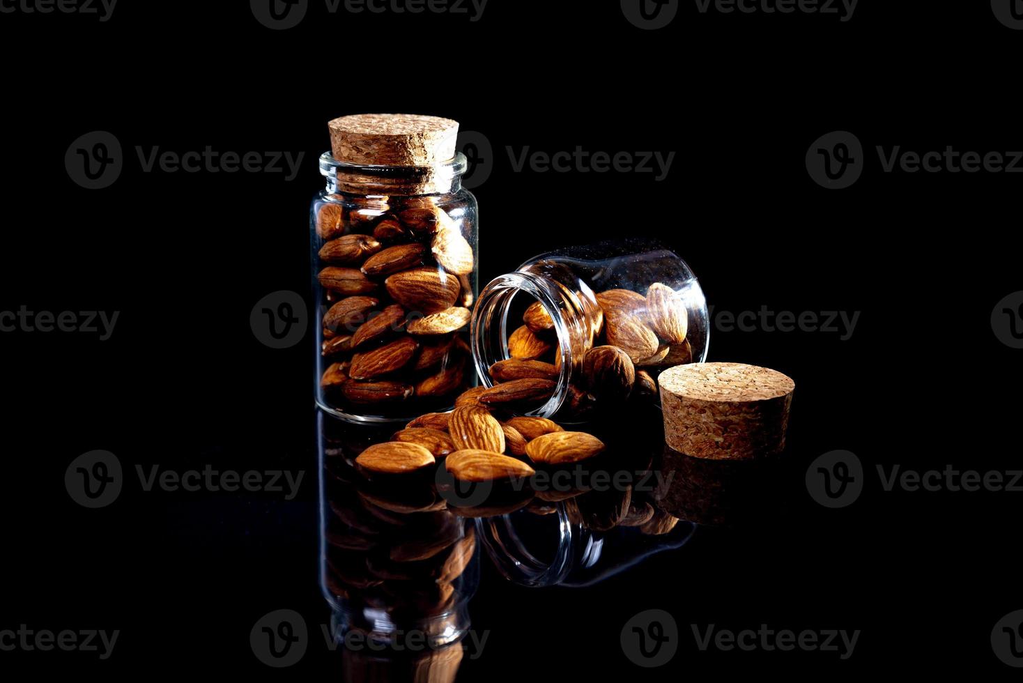 amandes pelées dans un seau de verre à vin en pot sur fond noir isolé. rangée de bols aux amandes, vue de face. photo