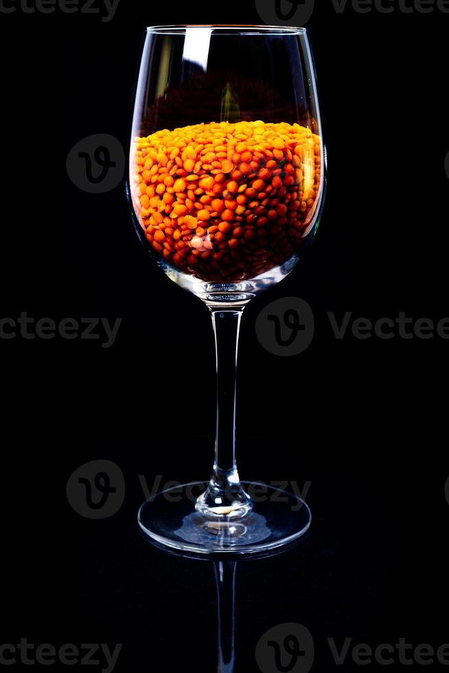 Close up of raw masur dal ou lentilles masoor ou lentilles roses dans un bol d'argile de couleur noire sur fond noir dans un seau en verre de verre à vin photo