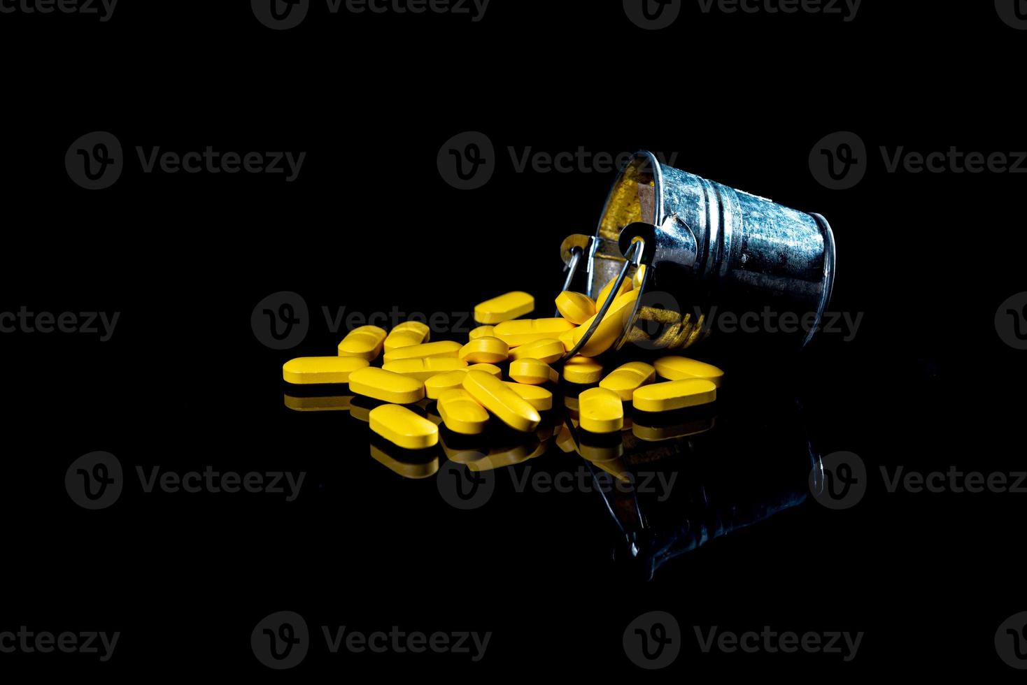 pilules oranges blanches dans un verre à vin. en pot. dans un seau isolé sur un ensemble noir de capsules et de pilules à l'intérieur de gros plan, photo