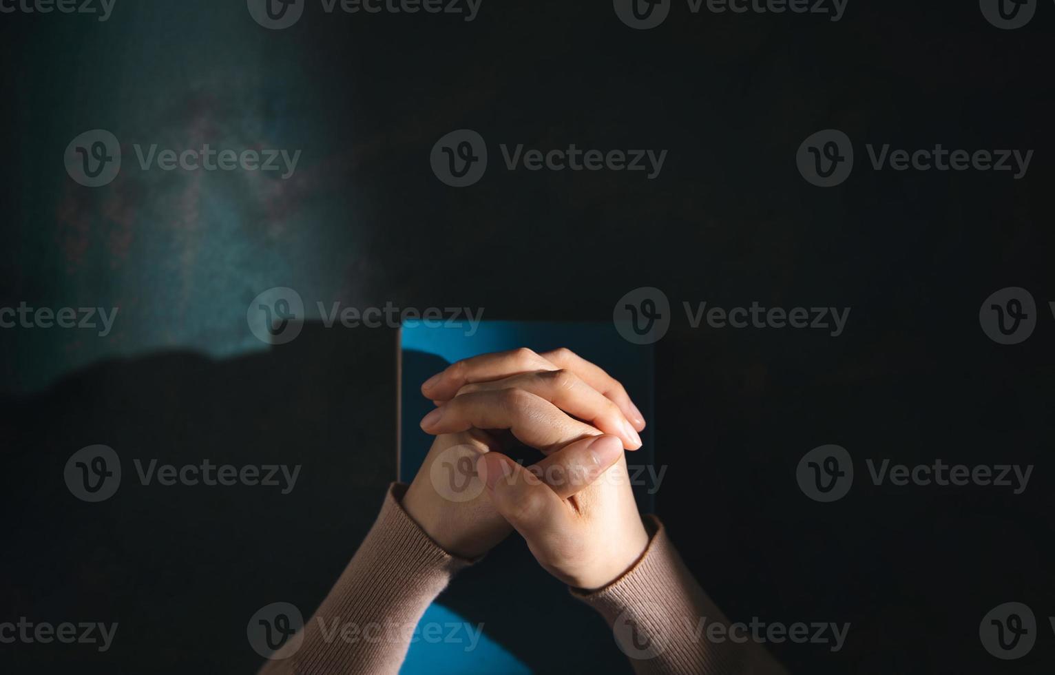 concept de spiritualité, de religion et d'espoir. personne priant par la sainte bible sur le bureau. symbole d'humilité, de supplication, de croyance et de foi pour le peuple chrétien. vue de dessus photo