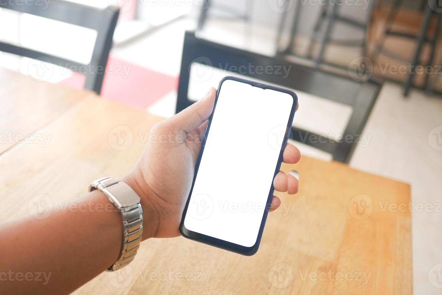 main de jeune homme utilisant un téléphone intelligent avec écran vert au café photo