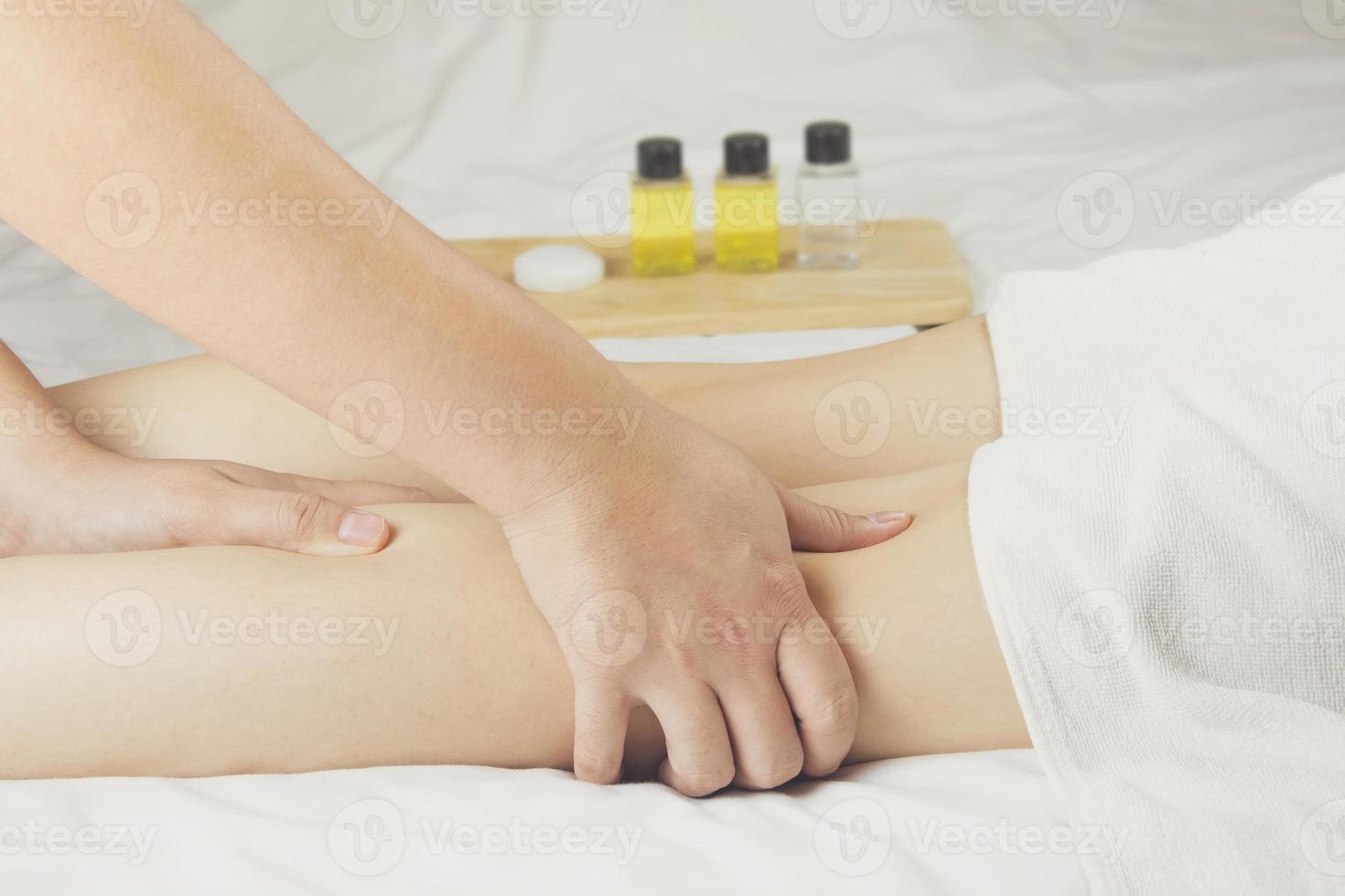 la main du massothérapeute masse les muscles du mollet de la jeune femme dans le salon de spa. concept de soins de santé, relaxation ou utilisation de produits naturels pour prendre soin de la peau des jambes photo