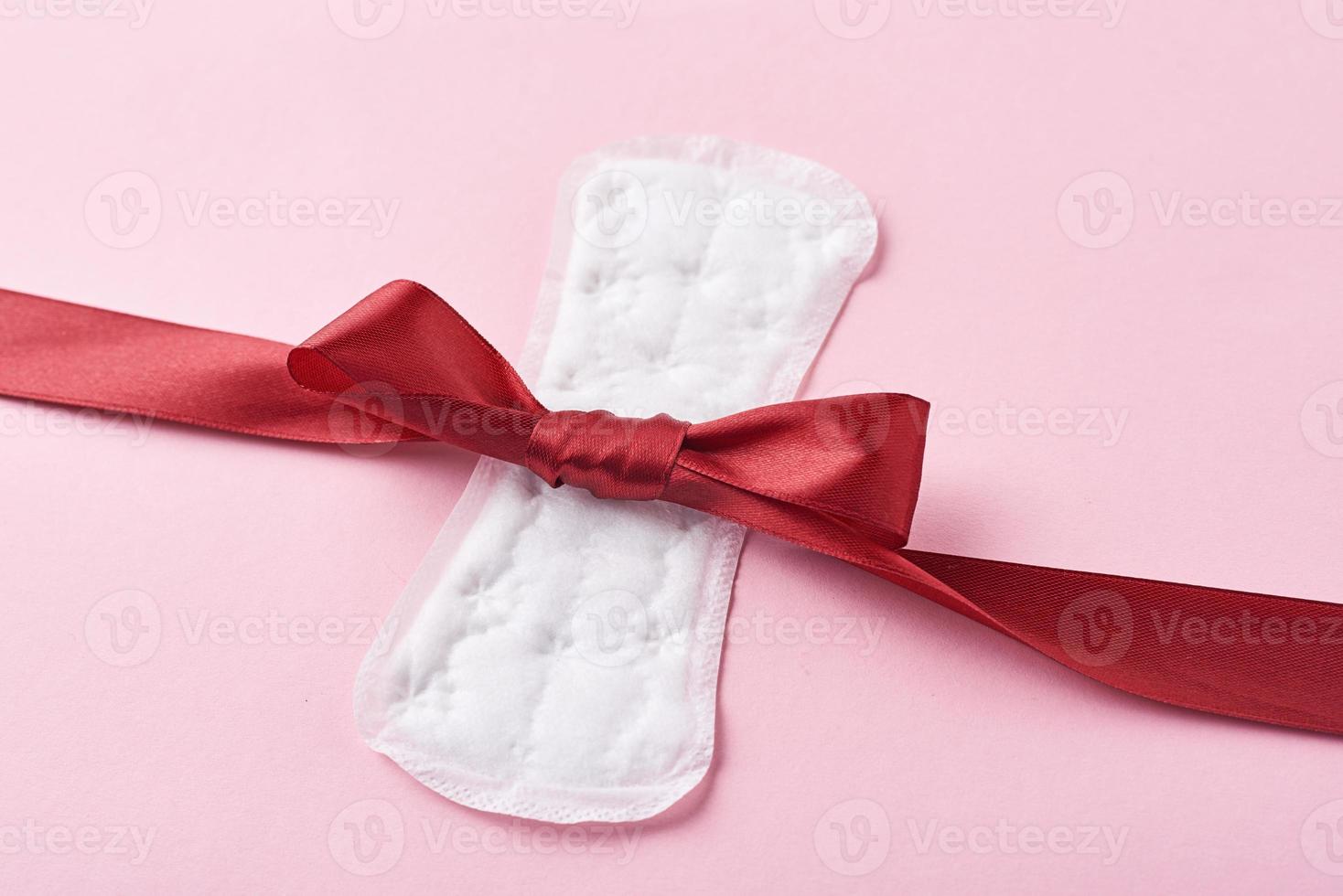 serviette hygiénique et ruban rouge sur fond rose photo