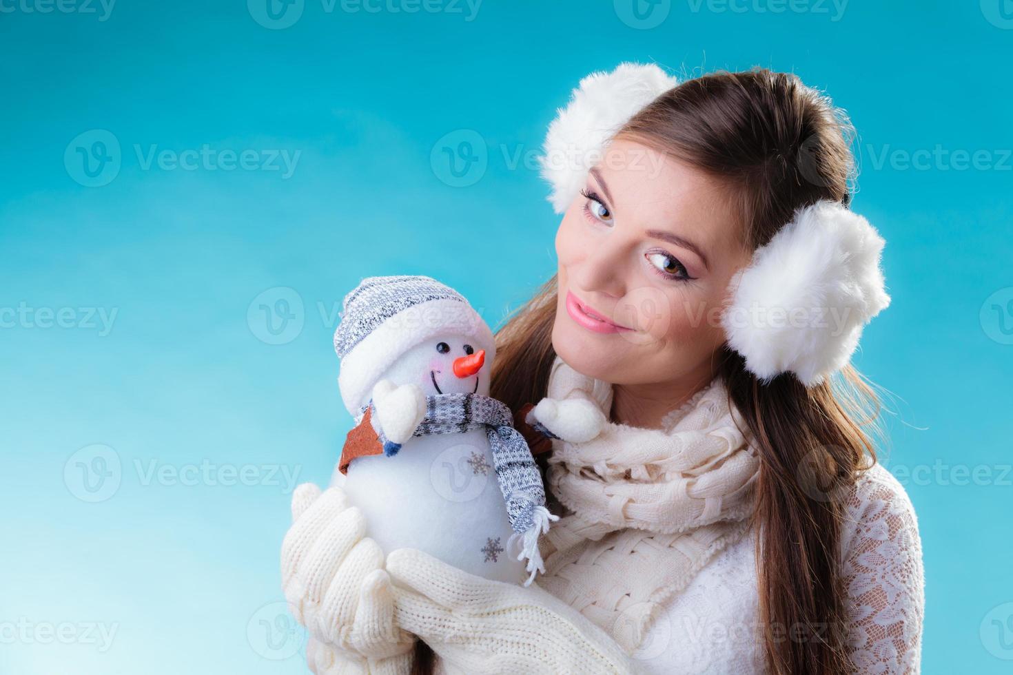 femme en vêtements chauds tenant le jouet de bonhomme de neige. photo