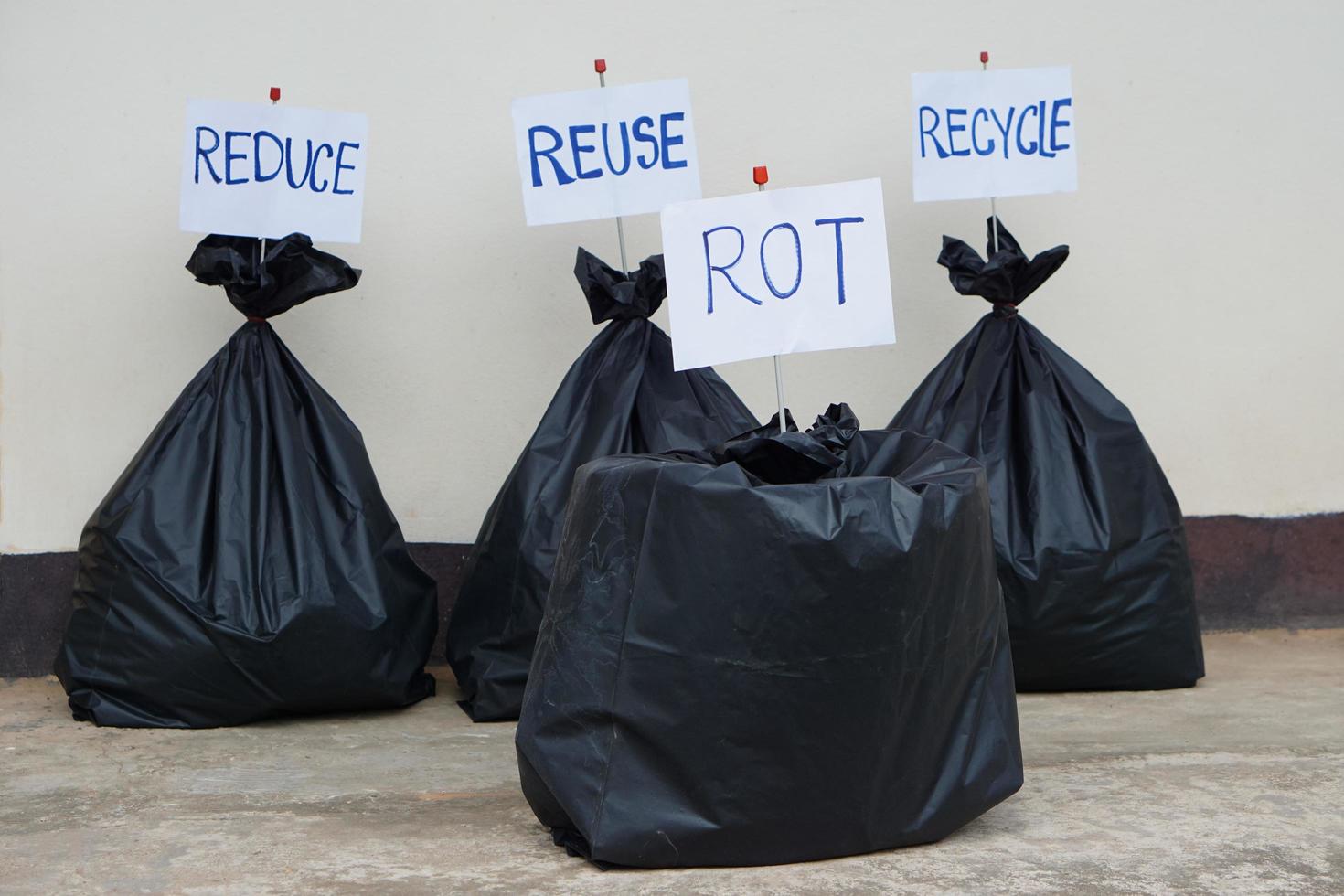 des panneaux en papier avec des mots recycler, réutiliser, réduire, pourrir, sur des sacs en plastique noirs contenant des ordures à l'intérieur. concept, gestion et tri des déchets. question d'environnement. photo