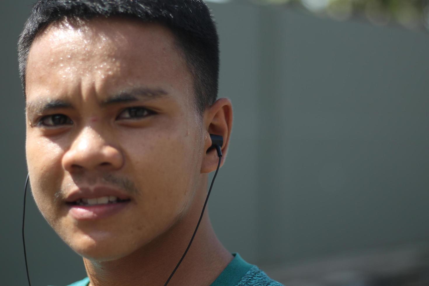 jeune garçon asiatique s'échauffant pour faire du jogging le matin et écouter de la musique photo