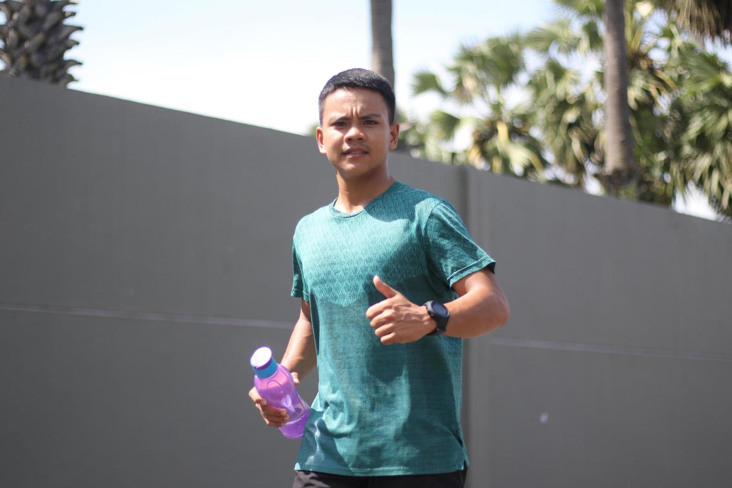 jeune garçon asiatique s'échauffant pour faire du jogging le matin et boire de l'eau minérale photo