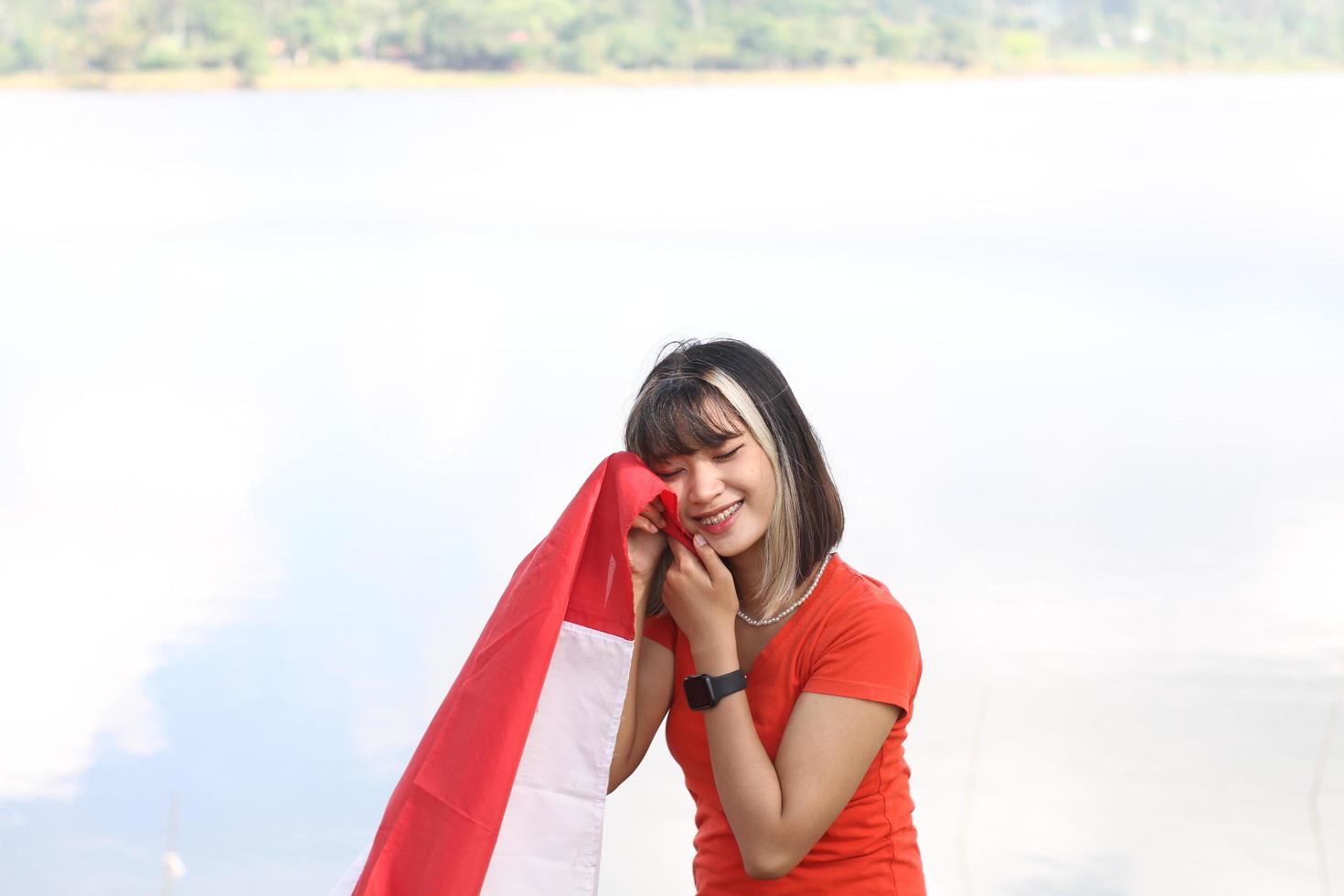 belle jeune femme asiatique portant le drapeau indonésien avec un visage joyeux photo