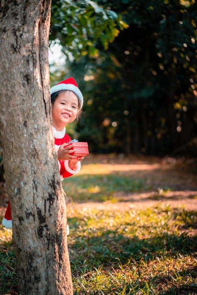 fille asiatique en costume de père noël rouge avec boîte cadeau photo