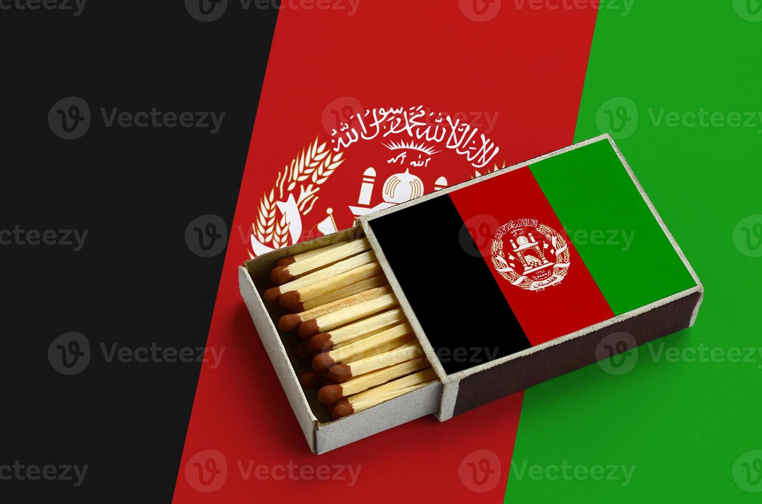 le drapeau de l'afghanistan est affiché dans une boîte d'allumettes ouverte, qui est remplie d'allumettes et repose sur un grand drapeau photo