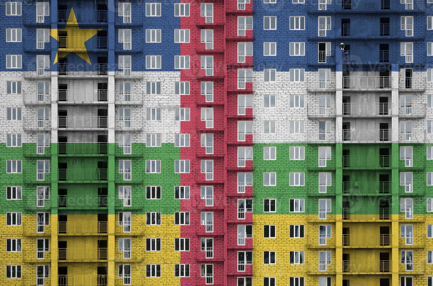 drapeau de la république centrafricaine représenté dans des couleurs de peinture sur un immeuble résidentiel à plusieurs étages en construction. bannière texturée sur fond de mur de brique photo