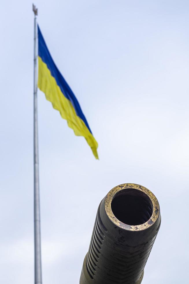 groupes d'anciens canons militaires dans le contexte du drapeau d'état de l'ukraine. frein de bouche d'un canon d'artillerie. ciel ensoleillé du matin. appel à arrêter le concept de violence. drapeau ukrainien. photo