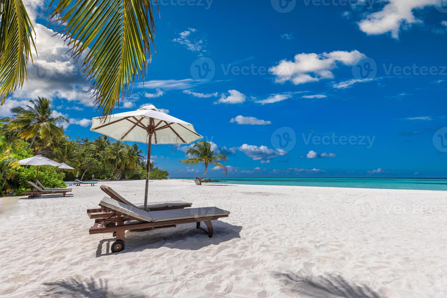 beau paysage tropical, couple chaises longues parasol sous les feuilles de palmier. fond d'été, plage de voyage exotique, côte paradisiaque ensoleillée. paysage incroyable, ciel de sable de mer relax resort vacances photo