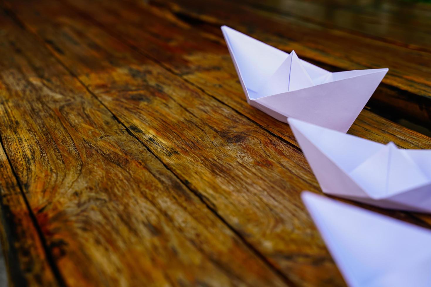 origami, bateau en papier blanc isolé sur un plancher en bois. les bateaux en papier signifient marcher. sentiment de liberté leadership photo