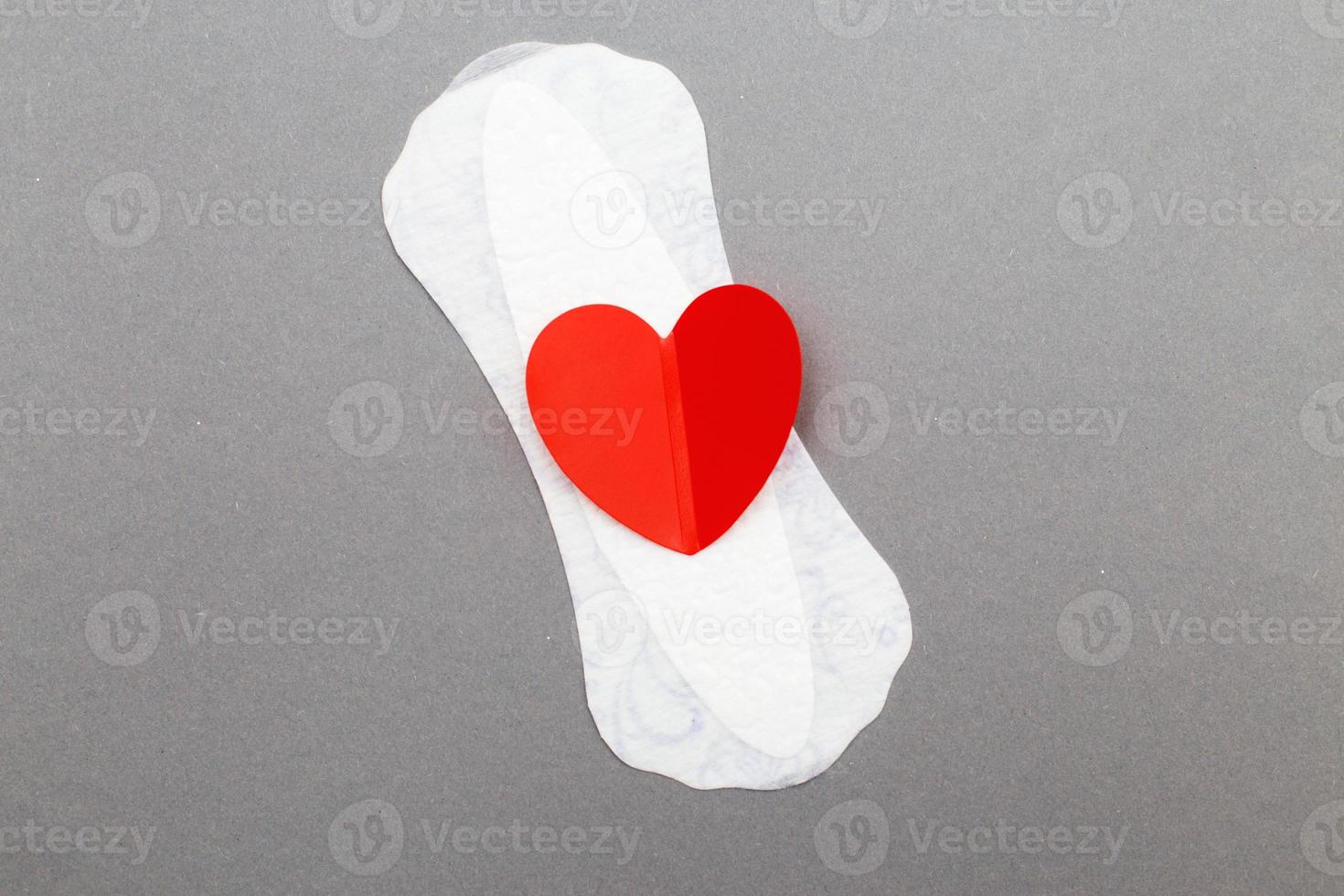 serviette hygiénique féminine avec un coeur rouge sur fond gris photo