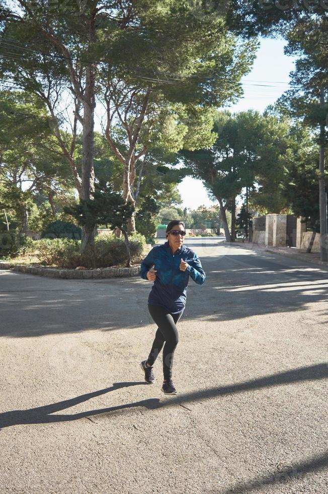 femme latine, d'âge moyen, portant des vêtements de sport, s'entraînant, faisant des exercices physiques, planche, redressements assis, pas d'escalade, brûler des calories, rester en forme, à l'extérieur au bord de la mer, porter des écouteurs, montre intelligente photo