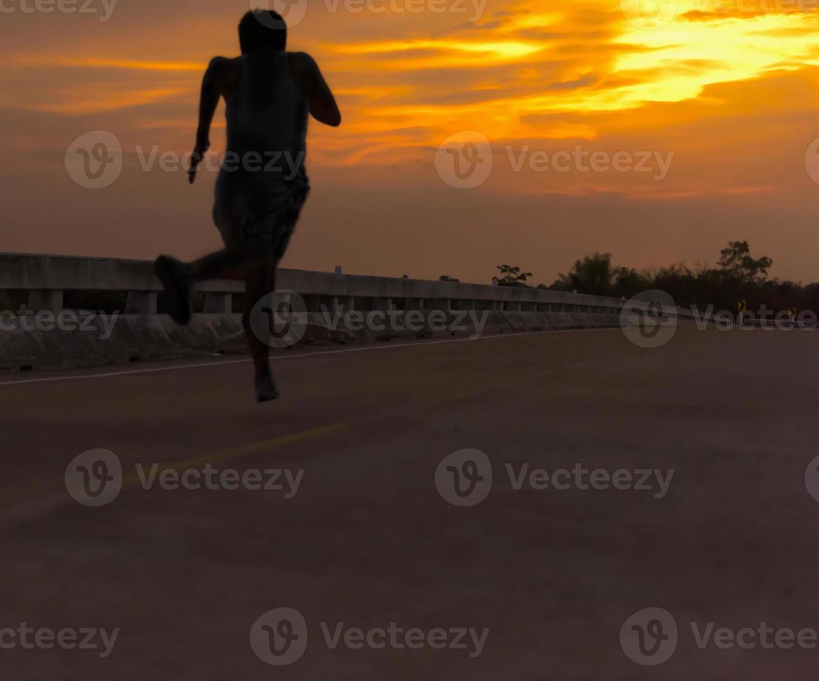 silhouette d'un homme courant vers le soleil sur un pont au crépuscule. photo