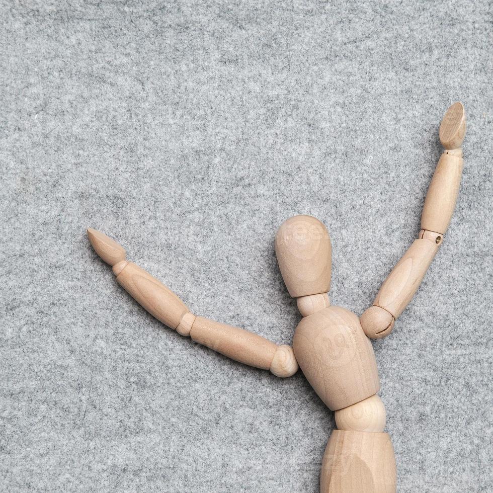 petite figurine en bois se réjouit, elle leva les mains pour représenter le bonheur, sur un fond de feutre gris. espace de copie. vue de dessus. photo