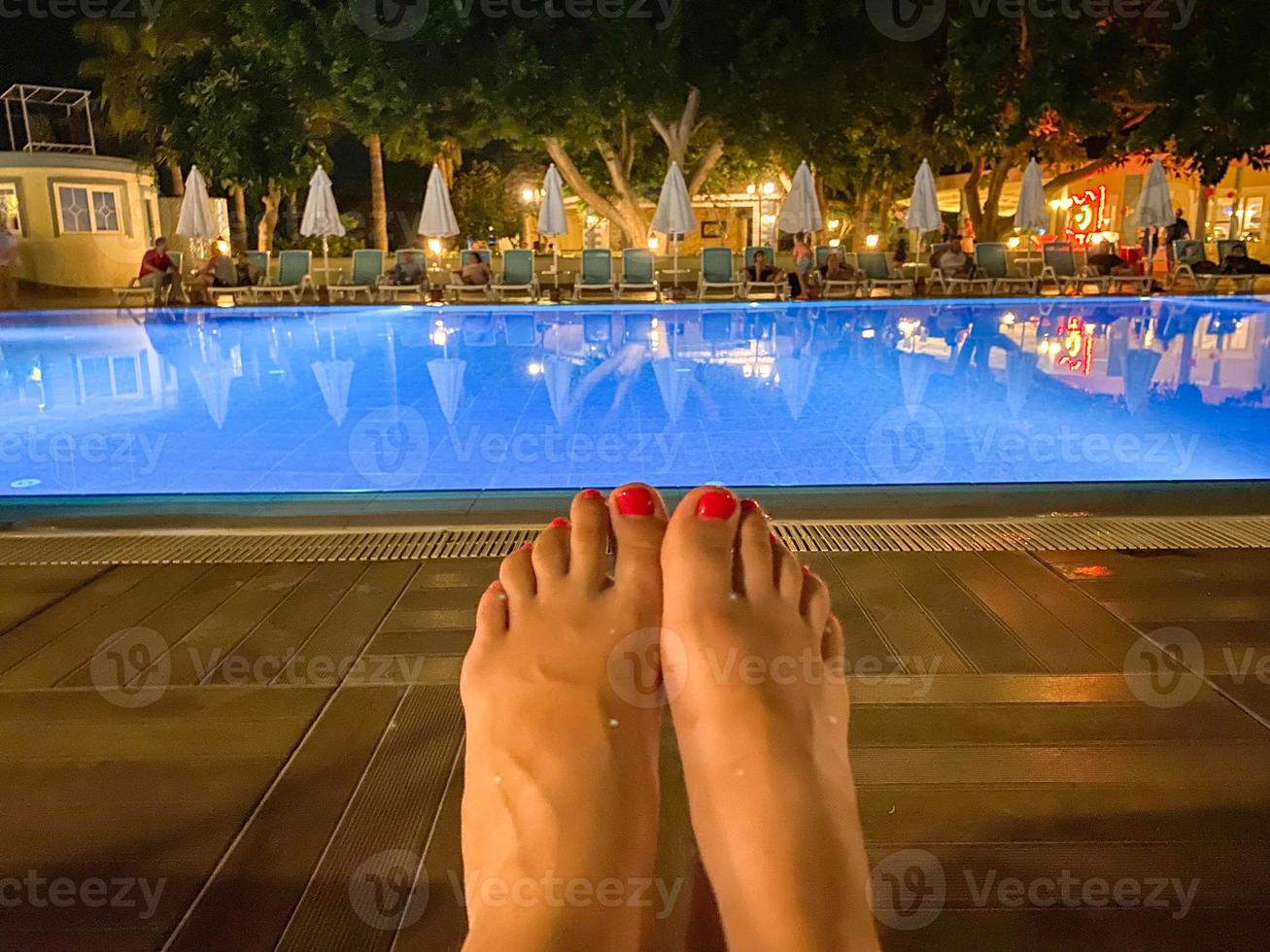 pieds de femme avec une belle manucure devant la piscine d'eau de l'hôtel tout compris la nuit dans un paradis oriental tropical chaleureux country resort du sud photo