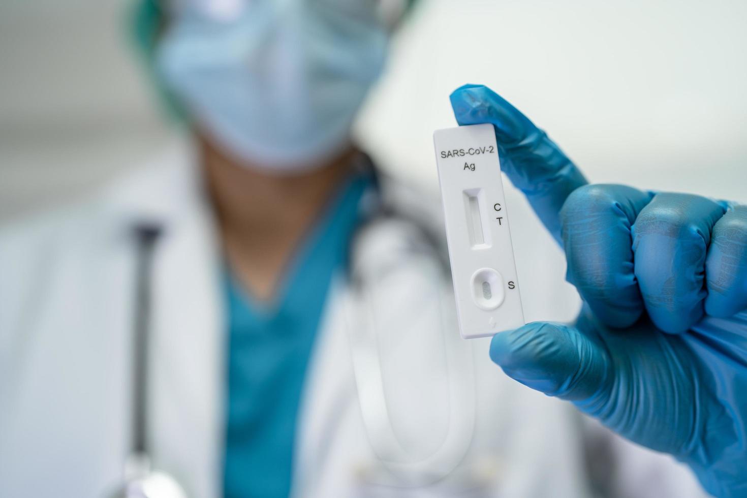 médecin asiatique en costume d'epi tenant un kit de test d'antigène salivaire pour vérifier le coronavirus covid19 à l'hôpital. photo