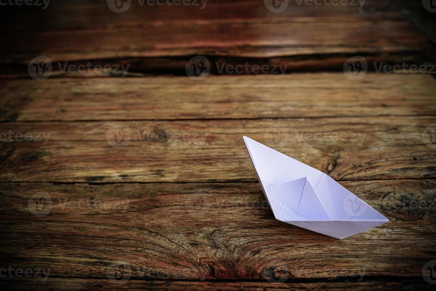 origami, bateau en papier blanc isolé sur un plancher en bois. les bateaux en papier signifient marcher. sentiment de liberté leadership photo