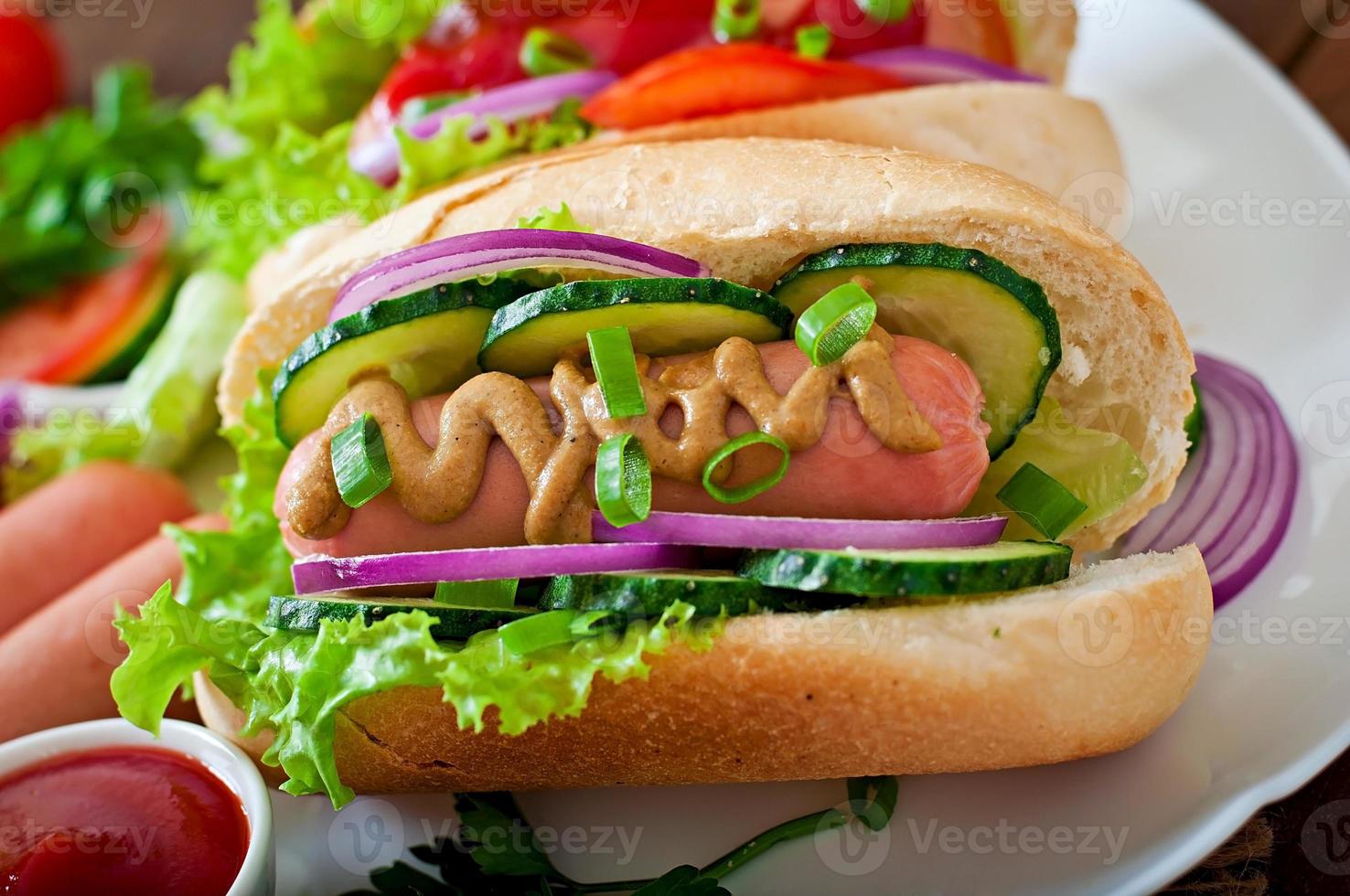 Hot-Dog avec du ketchup, de la moutarde, de la laitue et des légumes sur une table en bois photo