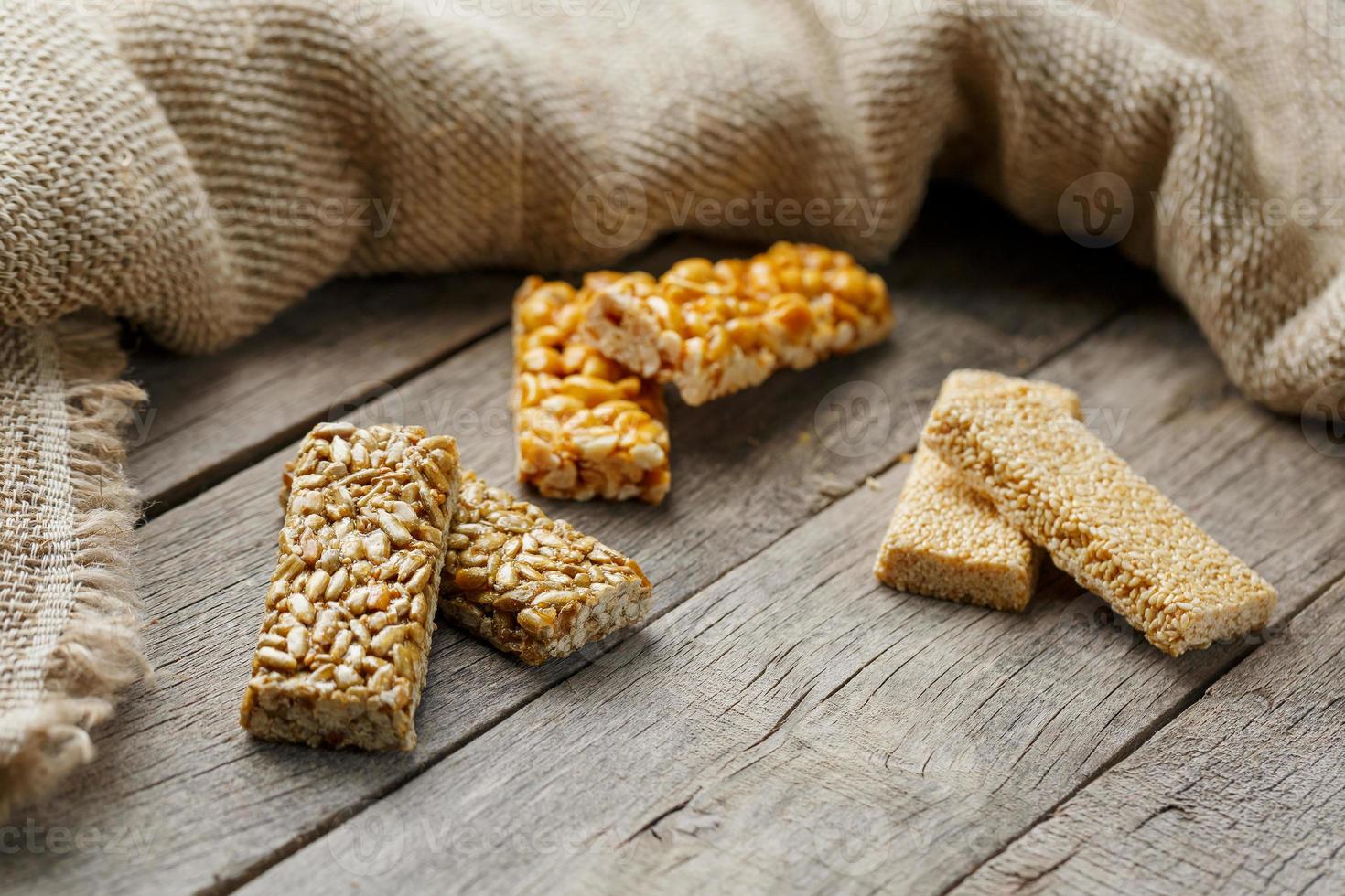 kozinaki assorti, sur fond vintage ancien, avec tissu de jute. style campagnard. délicieux bonbons à base de graines de tournesol, de sésame et de cacahuètes, recouverts d'une glaçure brillante. photo