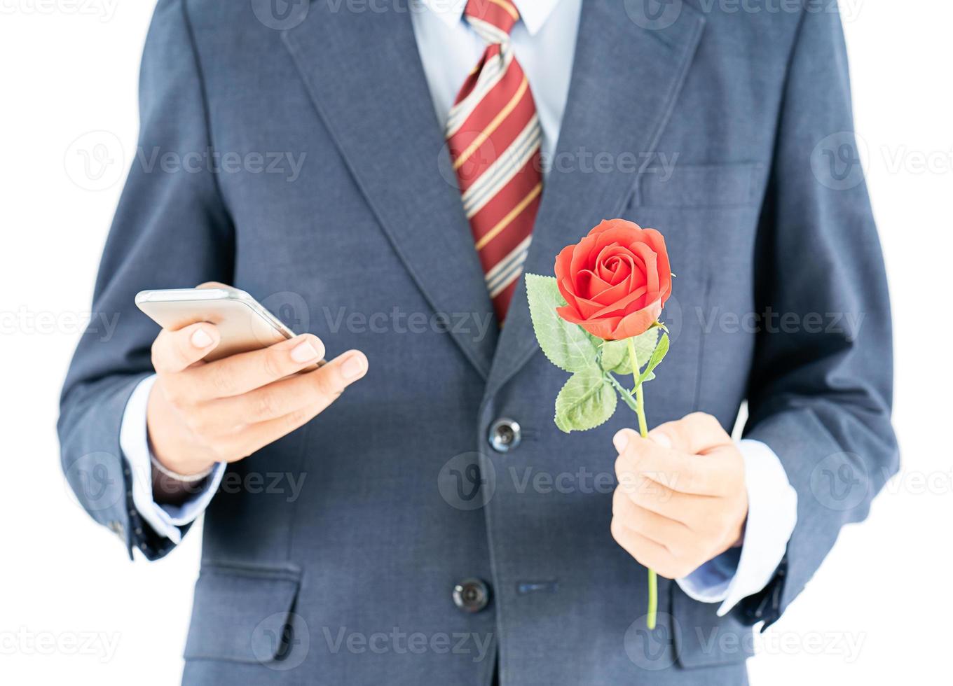 homme d'affaires en costume tenant un smartphone et une rose rouge photo