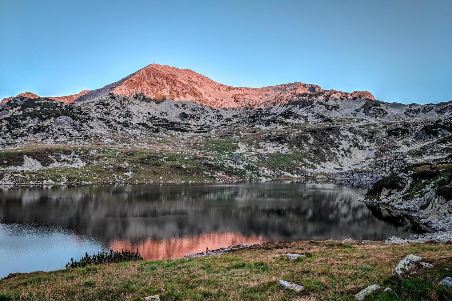 lever du soleil sur un sommet de montagne près d'un lac photo