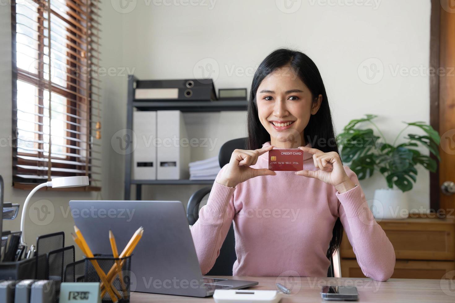 une femme d'affaires asiatique heureuse paie en ligne à l'aide d'un téléphone portable au bureau. photo