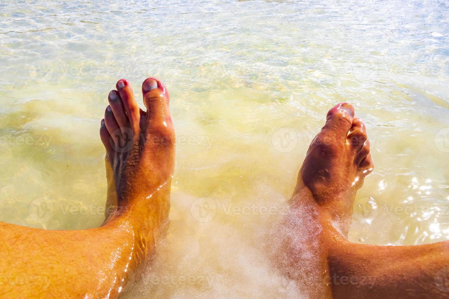 pieds dans une eau turquoise claire sur l'île de holbox au mexique. photo