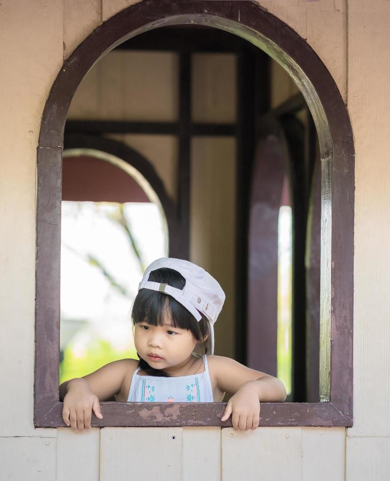 petite fille debout près de la fenêtre photo