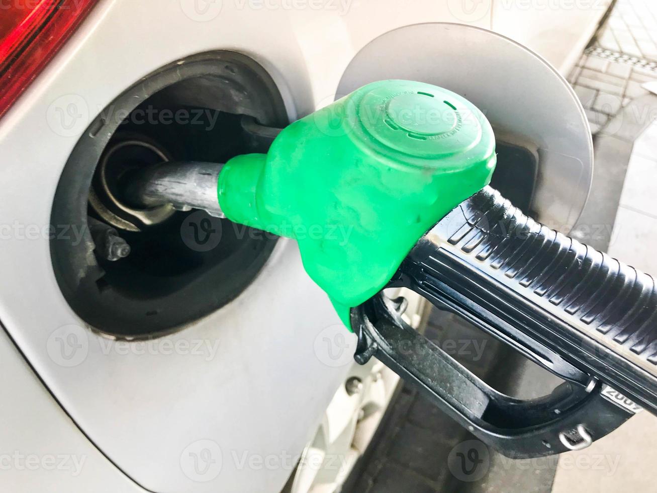 pistolet de remplissage vert coincé dans le réservoir d'essence d'une voiture à une station-service. le processus de remplissage de la voiture avec du carburant, de l'essence, du diesel photo