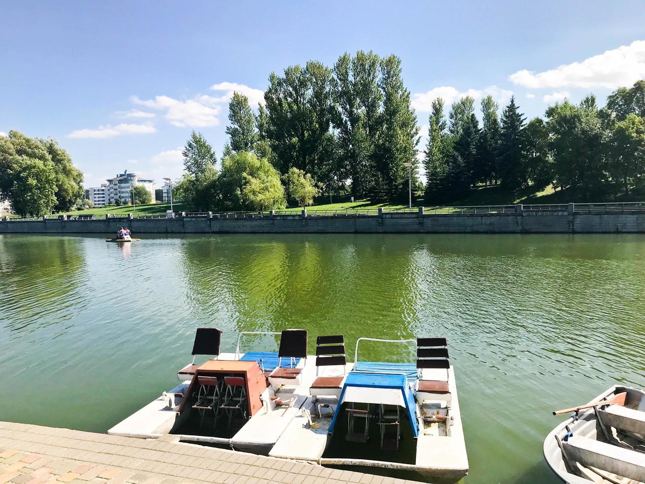 bateaux et catamarans sur un lac d'étang dans un canal fluvial avec de l'eau fleurie verte sont amarrés sur la rive photo