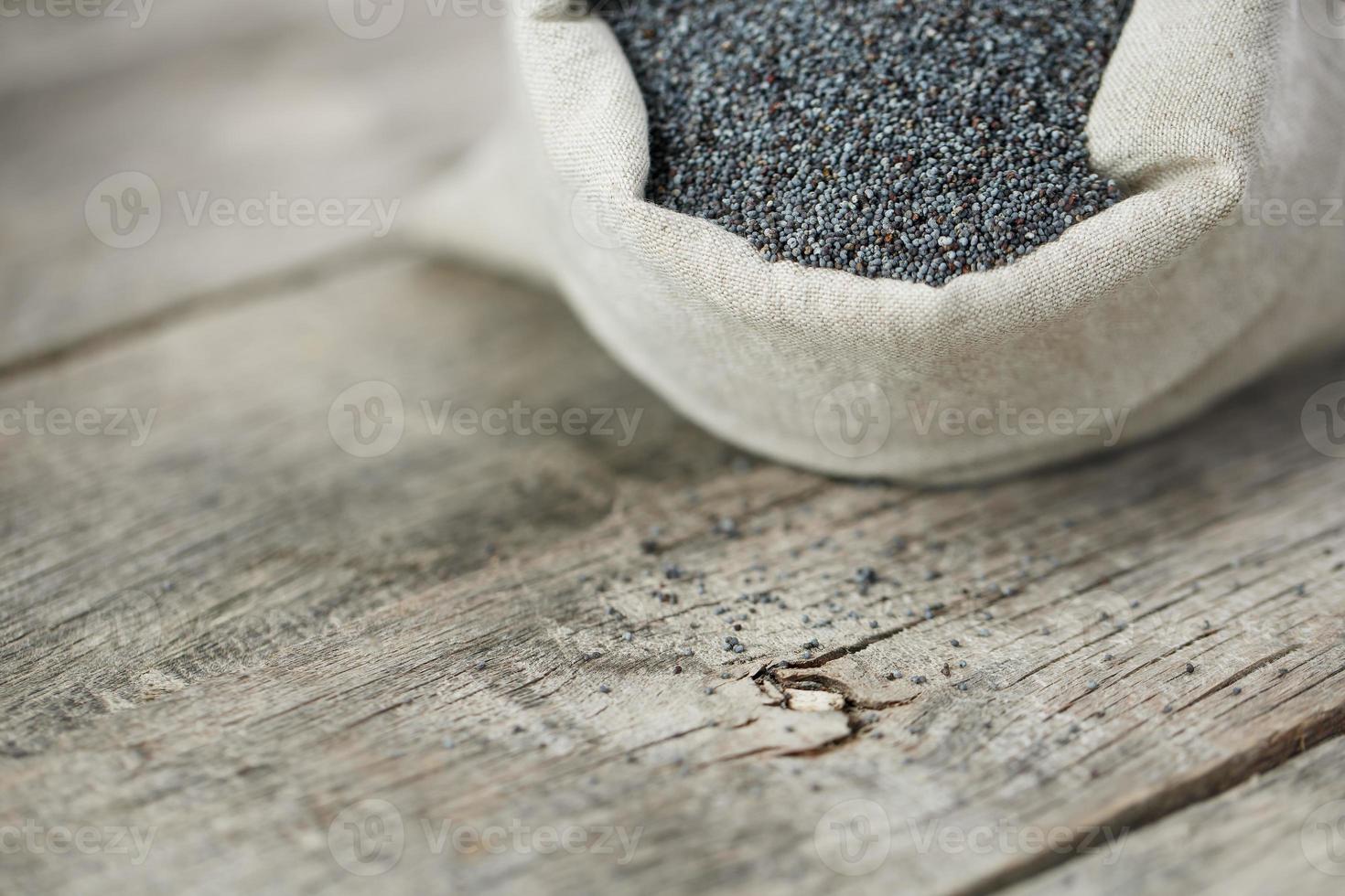 graines de pavot dans un sac de jute sur un fond gris en bois vintage. les graines savoureuses et utiles riches en protéines et en huiles. photo