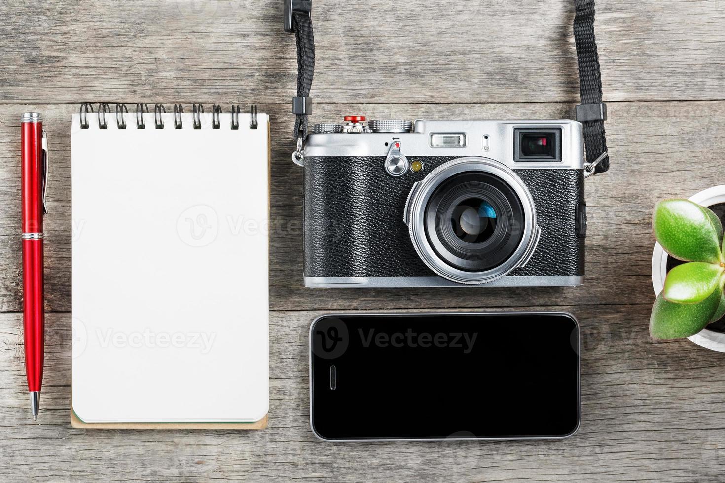 appareil photo classique avec page de bloc-notes vierge et stylo rouge sur un bureau vintage en bois gris avec téléphone.