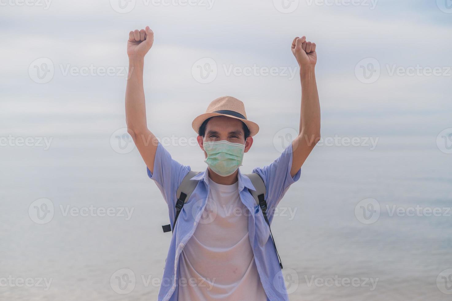 homme porter un masque facial tenant un sac voyager sur la plage photo