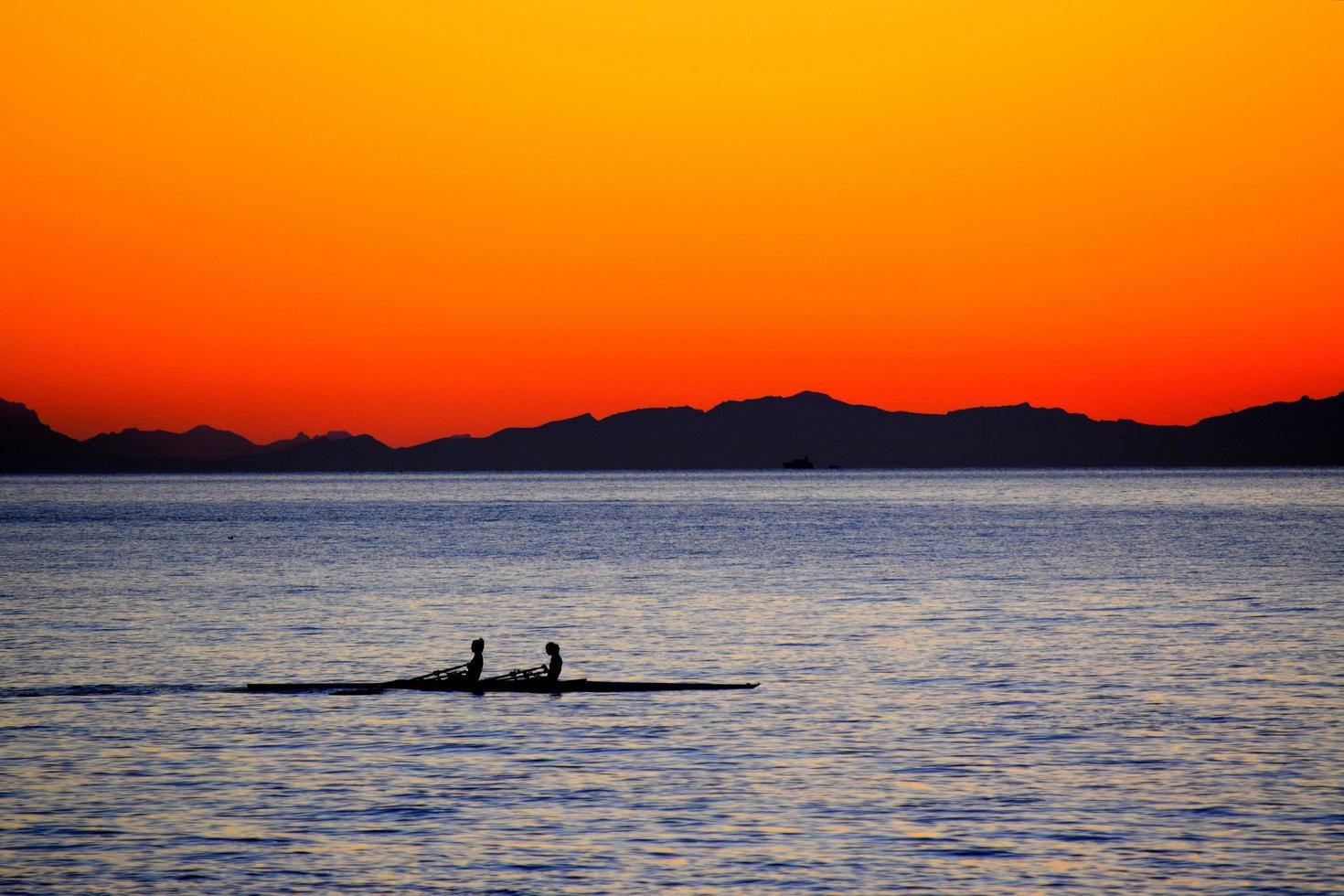 silhouette de deux personnes sur des barques au coucher du soleil photo