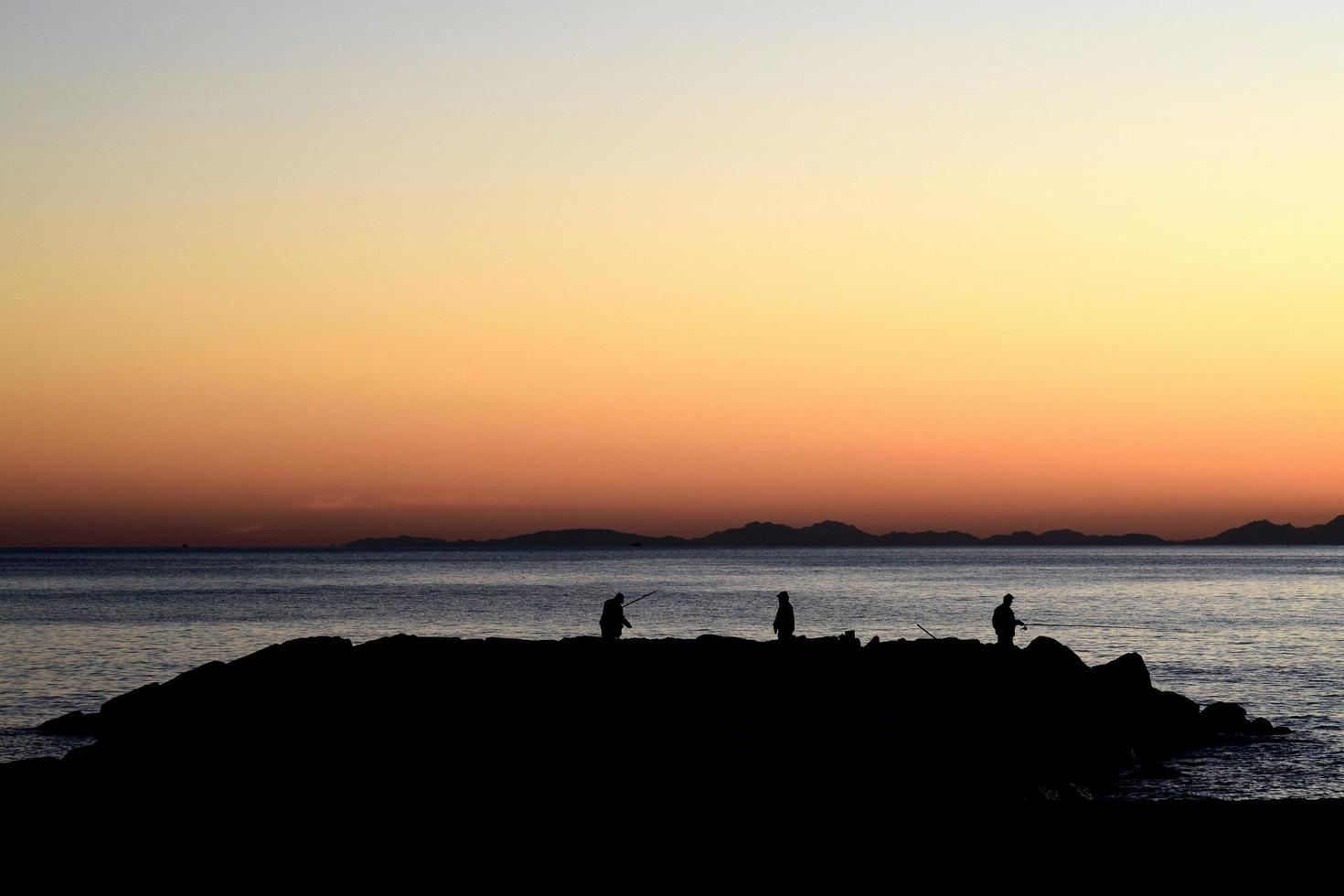 silhouette de trois pêcheurs sur l'île pendant l'heure d'or photo