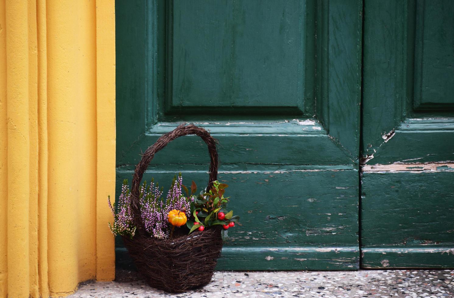 panier brun rempli de fleurs près de la porte colorée photo