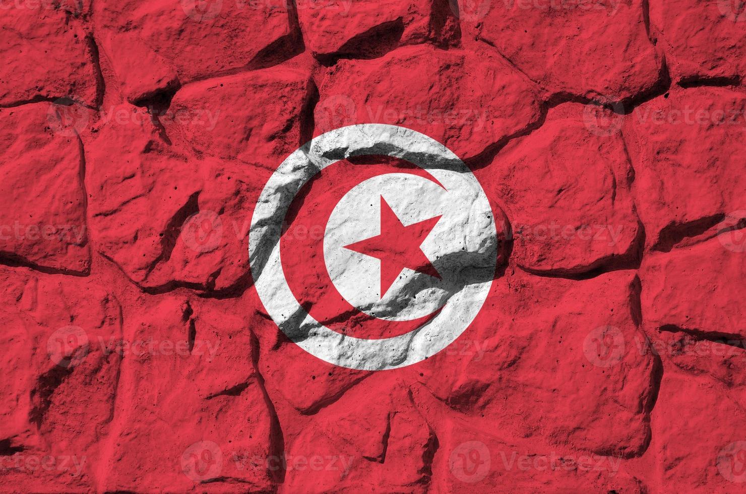 drapeau de la tunisie représenté dans des couleurs de peinture sur un vieux mur de pierre agrandi. bannière texturée sur fond de paroi rocheuse photo