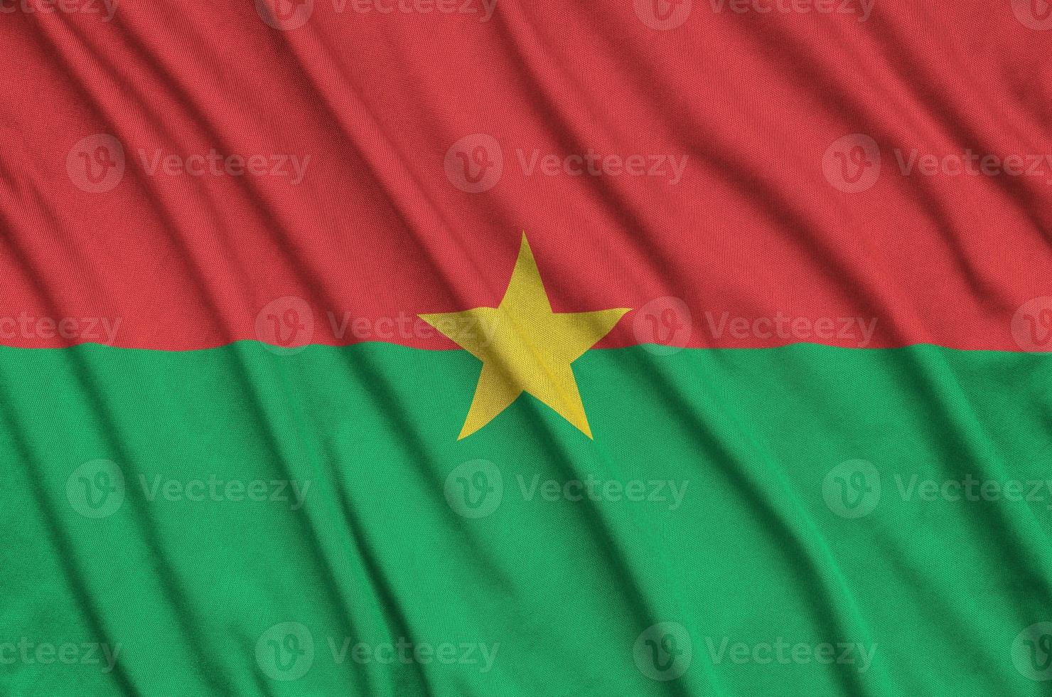 le drapeau du burkina faso est représenté sur un tissu de sport avec de nombreux plis. bannière de l'équipe sportive photo