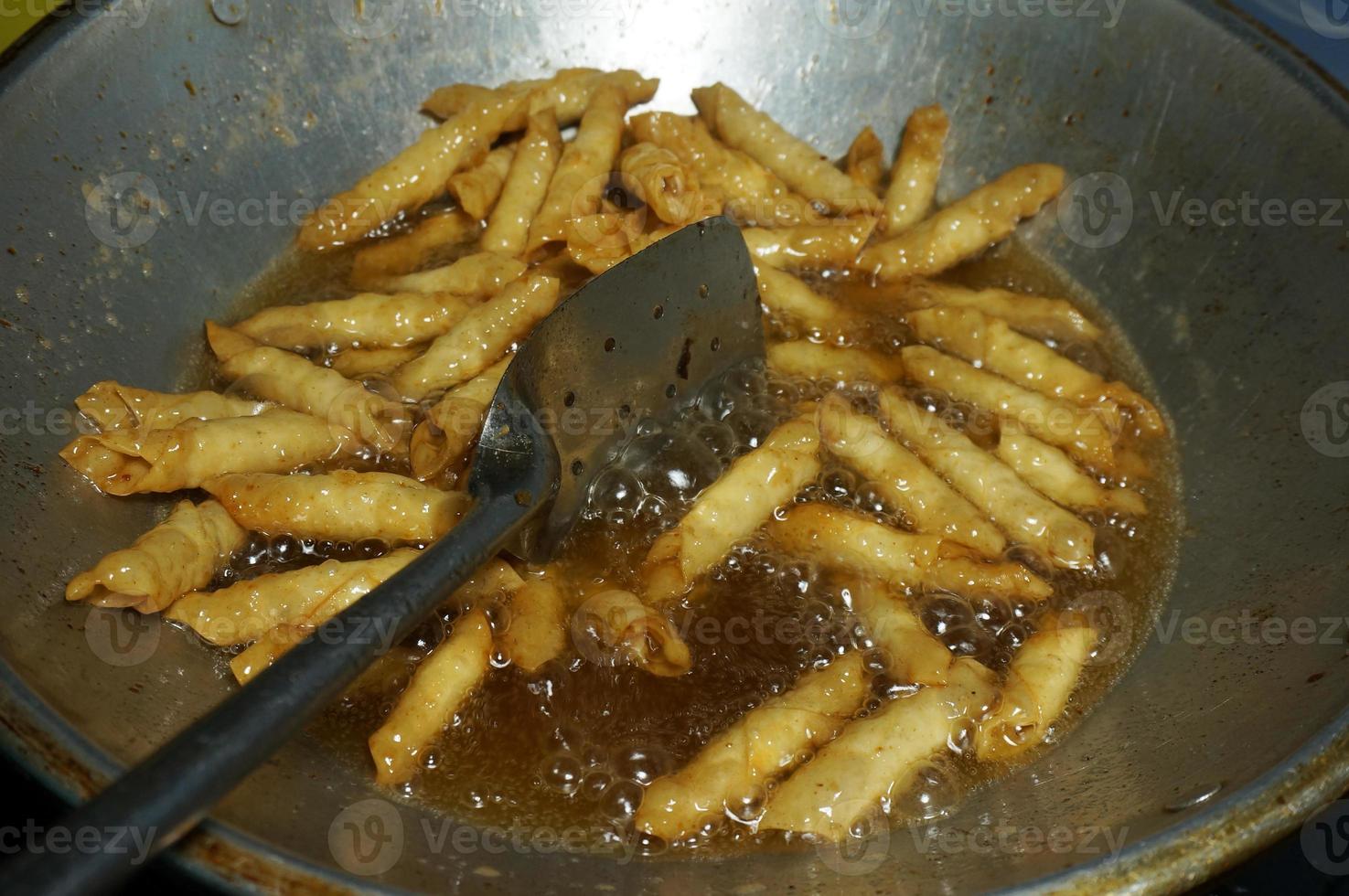 le processus de fabrication ou de cuisson d'un kacang sembunyi, collation populaire d'indonésie. haricots enveloppés dans une peau de pâte à base de farine . frits avec de l'huile et du sucre liquide. photo